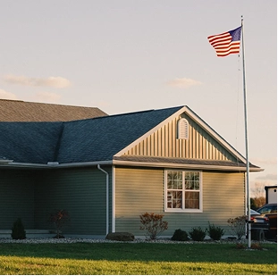 House with an American flag on a tall flagpole in the front yard.